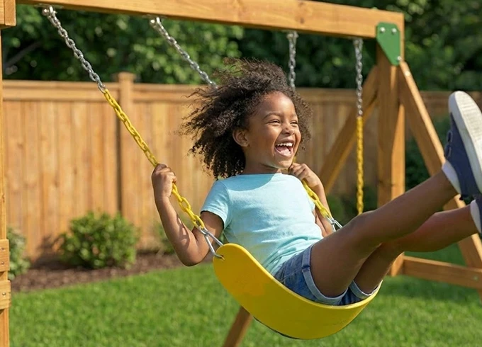 Kid playing on backyard playset swing